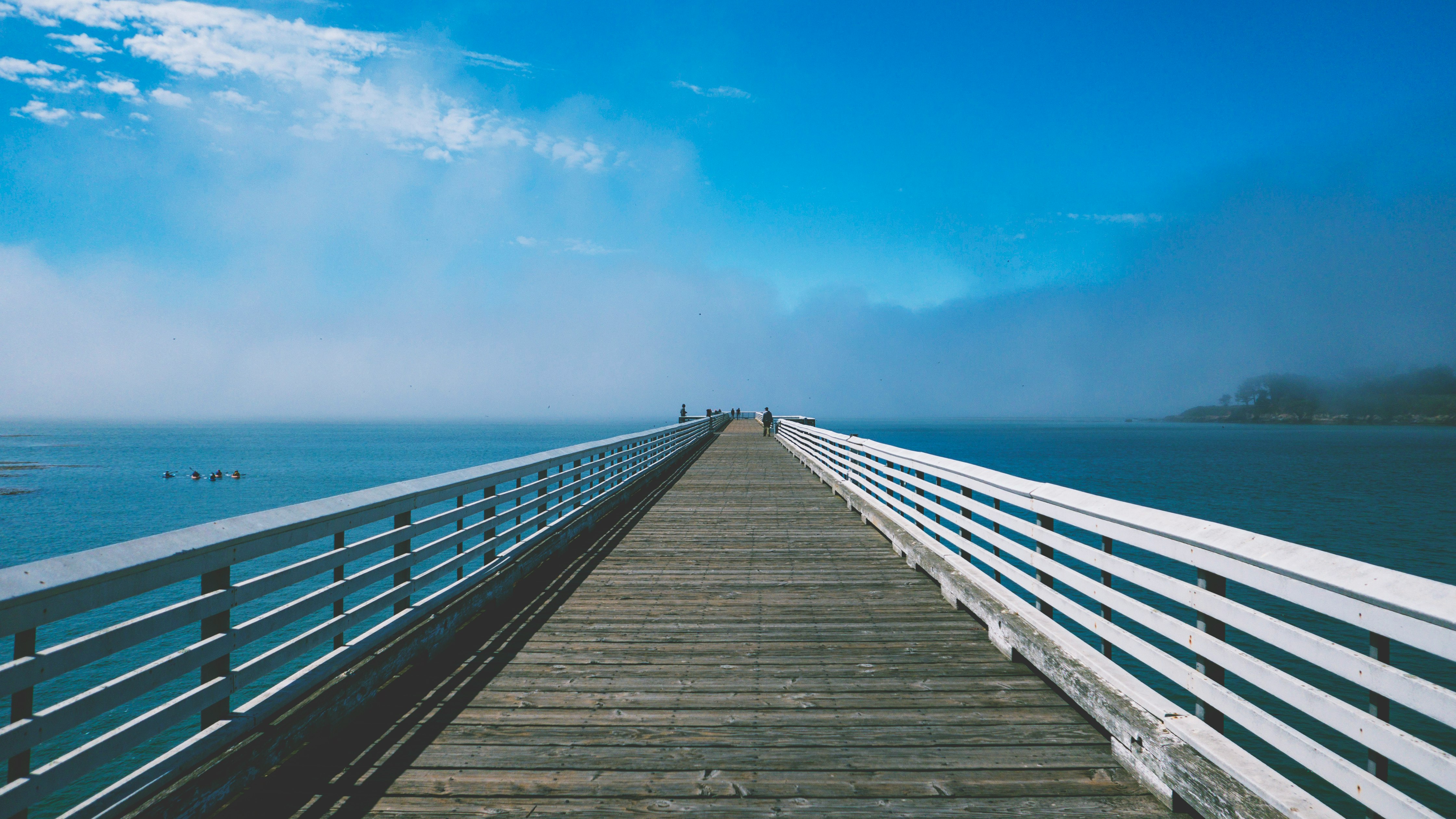 gray and white wooden sea dock under blue and white sky at daytime